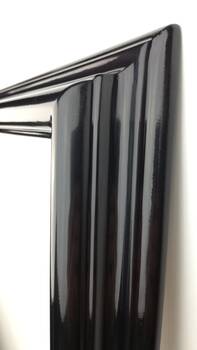 Detail of the undulating profile of the black lacquered mirror frame — deep gloss finish