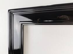 Zbliżenie narożnika czarnej oprawy – klasyczne lustro do salonu