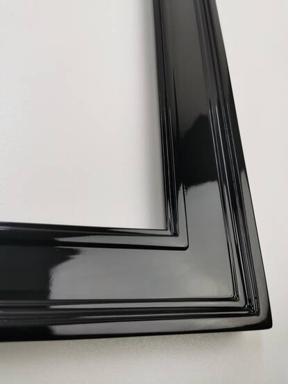 Close-up of a corner of a black high-gloss mirror frame, 52 mm moulding