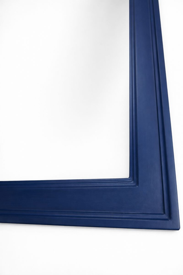 Close-up of the corner of a mirror in a blue frame — visible profiled moulding with a stepped cross-section and hand-applied multi-layer paint.