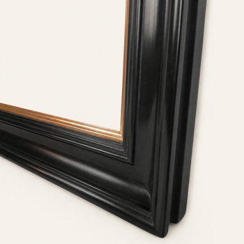 Corner of a black and gold gilded picture frame: the gold inner frame and the deep black profile, mitred at 45°.