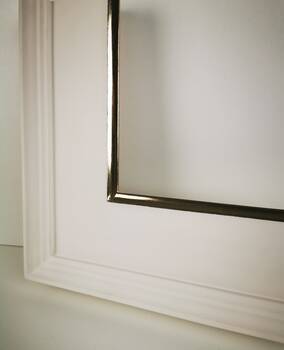 Close-up of the picture frame corner with hand-applied 22K moon gold accents on an off-white surface.