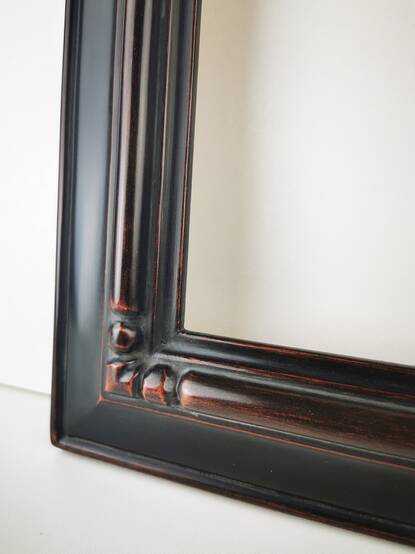 Zbliżenie rzeźbionego rogu czarnej ramy do obrazu z litego drewna