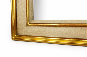 Zbliżenie struktury listwy ramy do obrazu, malowanej na złamaną biel z kontrolowanym efektem spękania i ręcznym złoceniem płatkowym.