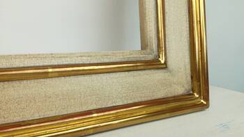 Detal narożnika drewnianej ramy łączonej na wpusty, wykończonej złamanym kolorem bieli z efektem spękania i złotem płatkowym 23K.