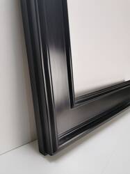 Detal powierzchni czarnej ramy lustra z delikatnym satynowym połyskiem.